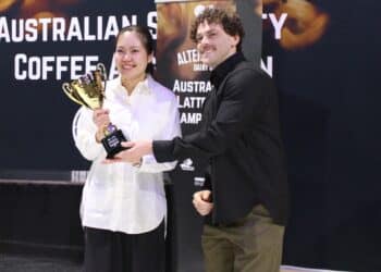 Jack Simpson presents Amy Zhang with the 2026 Australian Latte Art Championship trophy.