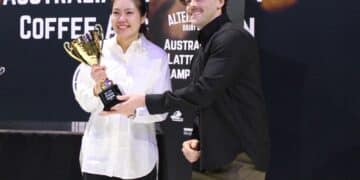 Jack Simpson presents Amy Zhang with the 2026 Australian Latte Art Championship trophy.