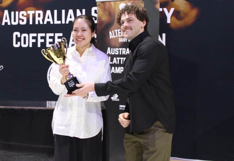 Jack Simpson presents Amy Zhang with the 2026 Australian Latte Art Championship trophy.